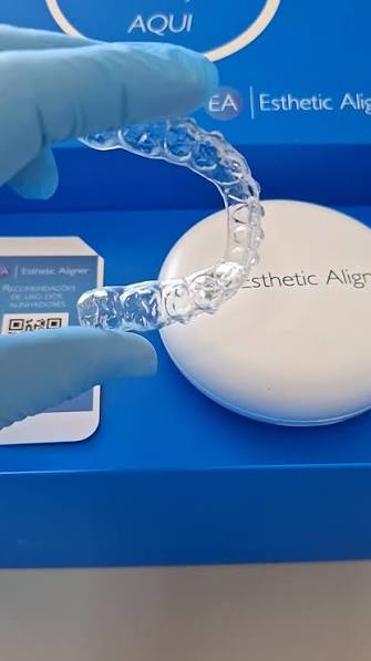 Alinhador transparente sendo segurado com luvas